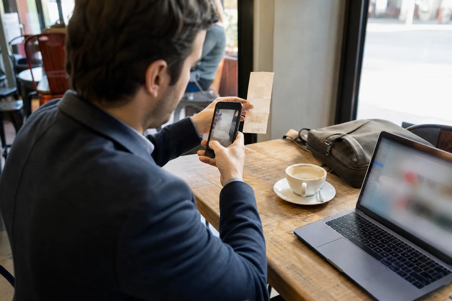 Client snapping a photo of a lunch receipt at a cafe table