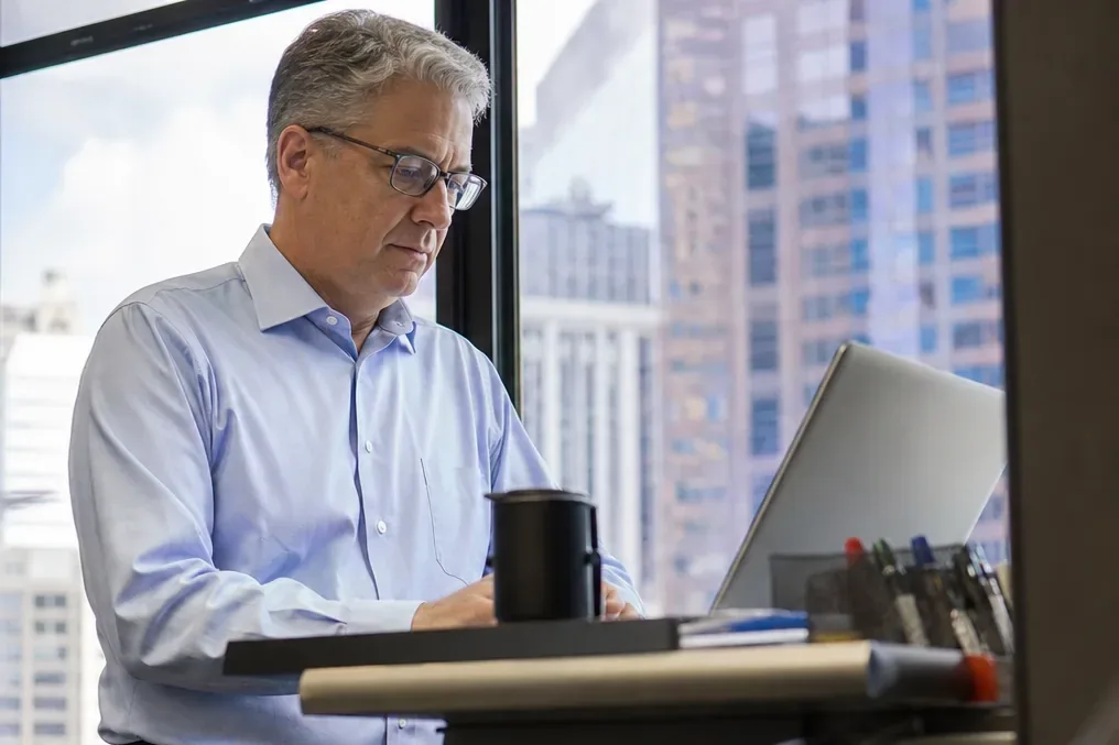 Accounting firm partner at a standing desk checking software costs on a laptop