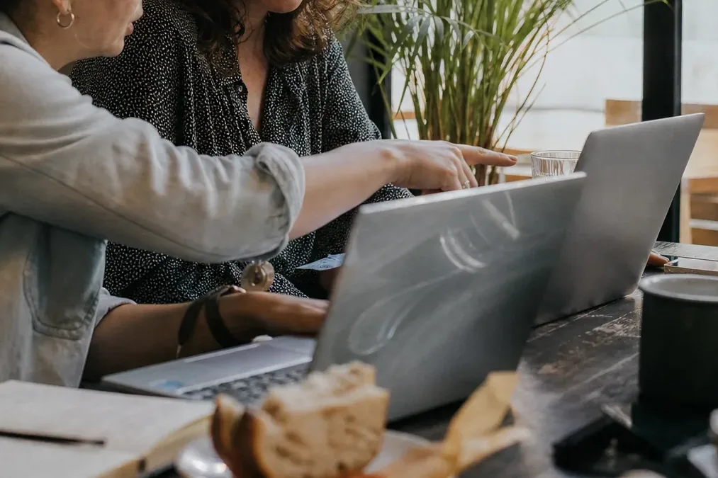 Two laptops on a shared table as two bookkeepers compare receipt workflows